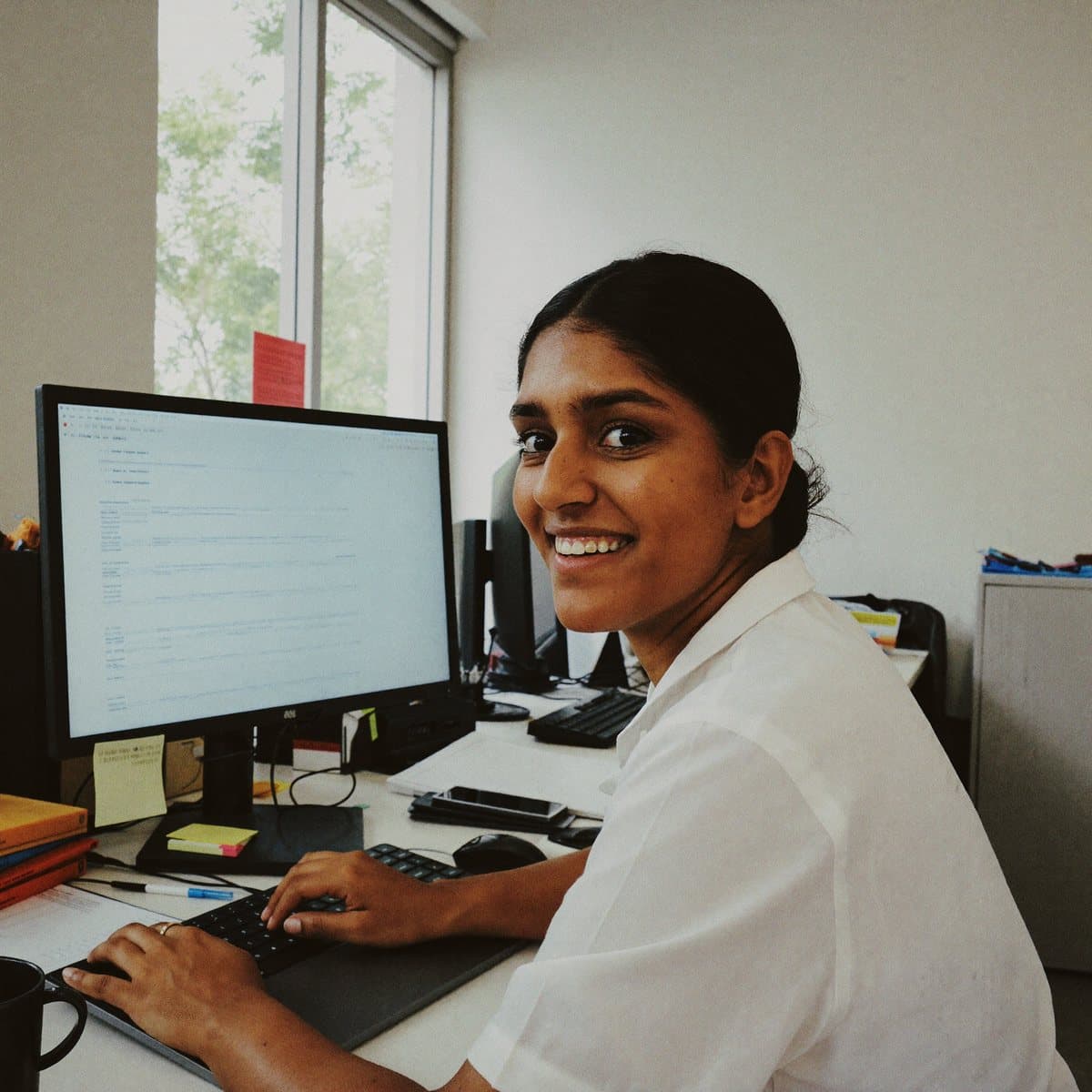 An accountant at her desk in an office, looking up from her keyboard. Illustrative photography, not a Proofed Talent member.